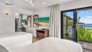 A hotel room with a large bed, a nightstand, a mirror, and a painting of a beach scene. - Wailea Elua 1104 - Ocean Views, Central A/C, Walk to Ulua Beach, Shops & Dining! (Kihei)