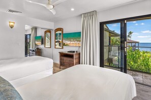 A hotel room with a large bed, a nightstand, a mirror, and a painting of a beach scene. - Wailea Elua 1104 - Ocean Views, Central A/C, Walk to Ulua Beach, Shops & Dining! (Kihei)