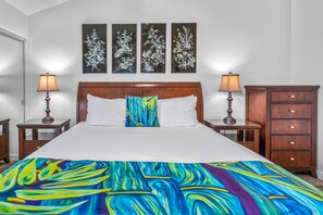 A hotel room with a large bed, two bedside tables, a nightstand, a dresser, and three wall-mounted artworks. - Wailea Elua 1104 - Ocean Views, Central A/C, Walk to Ulua Beach, Shops & Dining! (Kihei)