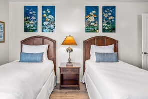 A hotel room with two beds, a nightstand with a lamp, and three wall-mounted paintings. - Wailea Elua 1104 - Ocean Views, Central A/C, Walk to Ulua Beach, Shops & Dining! (Kihei)