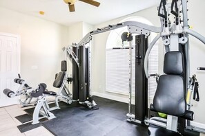 Et hjemmegymnasium med en squat-stander, bænkpress og forskellige træningsmaskiner.