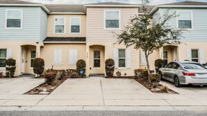 A row of townhouses with a central entrance, a driveway, and a parked car. - Tranquil Vacations - Kissimmee (Kissimmee)