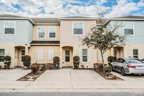 A row of townhouses with a central entrance, a driveway, and a parked car. - Tranquil Vacations - Kissimmee (Kissimmee)