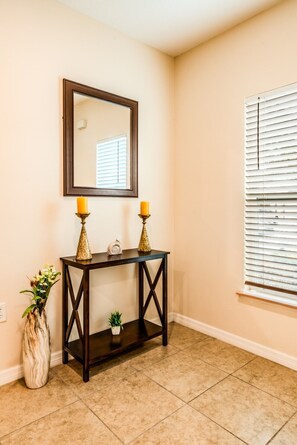 A room with a dark wooden console table, two candles, a small plant, and a mirror on the wall. - Tranquil Vacations - Kissimmee (Kissimmee)