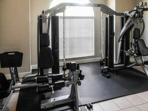 A gym with exercise equipment, a window with blinds, and a tiled floor. - Tranquil Vacations - Kissimmee (Kissimmee)