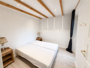 A bedroom with a bed, bedside tables, a lamp, a window with curtains, and a door with a handle. - Panoramic ocean view, direct access to a private sandy beach in Skagen South—family-friendly (Ålbæk)