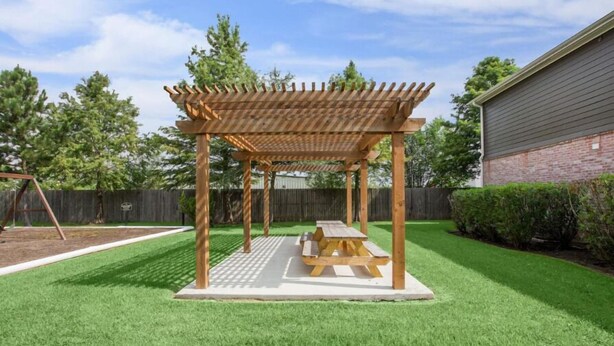 A wooden pergola with a picnic table in a backyard with artificial grass. - Kingsgate One Bedroom Stay (Beaumont)