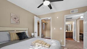 A bedroom with a large bed, a ceiling fan, and a bathroom visible through an open door. - Kingsgate One Bedroom Stay (Beaumont)