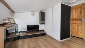 Una sala de estar moderna con un televisor de pantalla plana, pisos de madera, un mueble de madera y una puerta corrediza.