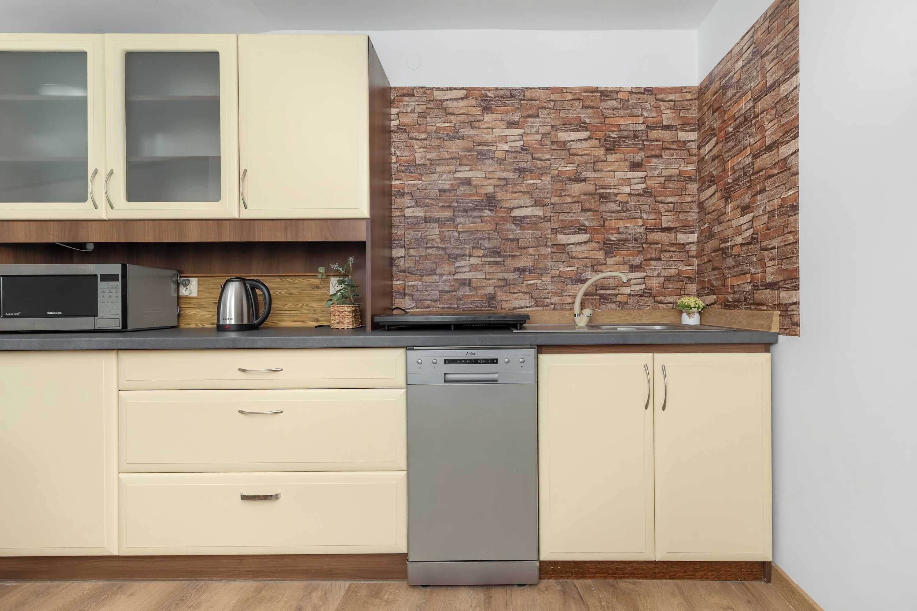 A compact kitchen with a microwave, kettle, and dishwasher.