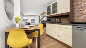 Una cocina moderna con sillas amarillas, una mesa de comedor y vistas a la ciudad a través de una ventana.