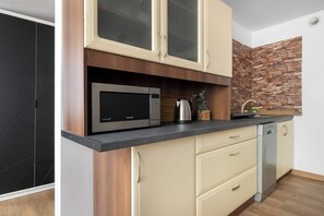 A modern kitchen with a microwave, kettle, and dishwasher. - A Stylish Studio for Two | Historic Nikiszowiec (Katowice)