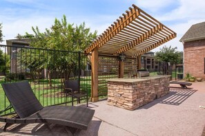 An outdoor patio with a grill, lounge chairs, and a pergola structure. - Comfortable Kingsgate 2BR (Beaumont)