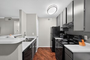 A modern kitchen with a stainless steel refrigerator, a double oven, and a built-in microwave. - Comfortable Kingsgate 2BR (Beaumont)
