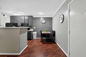 A compact kitchen with a dining area, featuring a clock and a mirror on the wall.