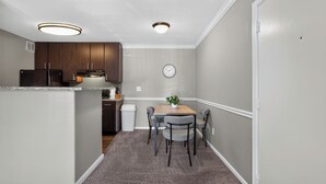 A compact kitchen with dark wooden cabinets, a built-in microwave, and a clock on the wall. - Relaxing Kingsgate 2BR (Beaumont)