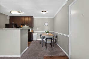A compact kitchen with dark wooden cabinets, a built-in microwave, and a clock on the wall. - Relaxing Kingsgate 2BR (Beaumont)