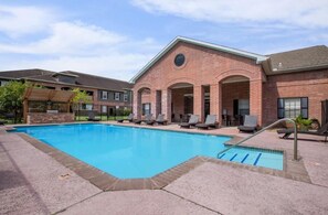 A swimming pool with lounge chairs and a covered seating area.