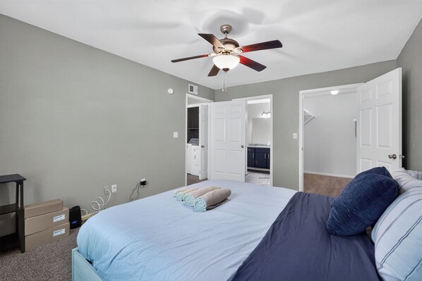 A bedroom with a bed, a ceiling fan, a dresser, and a closet.