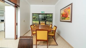 Uma sala de conferências com uma mesa comprida, cadeiras, um quadro e uma janela com vista para o verde.