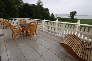 A balcony with a white picket fence, wicker furniture, and a view of a body of water. - Appartement im Seedomizil Kummerow (Kummerow)
