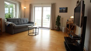 A living room with a sofa, a coffee table, a TV, and a plant. - Appartement im Seedomizil Kummerow (Kummerow)