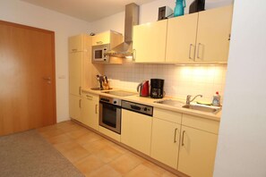 A compact kitchen with a microwave, oven, and dishwasher. - Appartement im Seedomizil Kummerow (Kummerow)