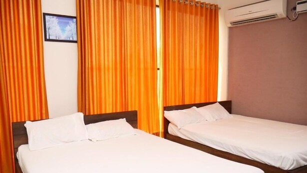 Una habitación de hotel con dos camas individuales, un cuadro en la pared y un equipo de aire acondicionado.