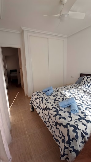 A bedroom with a bed, a wardrobe, and a ceiling fan.