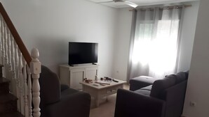 A living room with a TV, a coffee table, and two sofas.