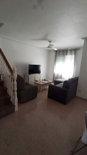A living room with a TV, a coffee table, and two sofas.
