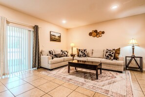 A living room with a sofa set, a coffee table, a lamp, a rug, and a painting on the wall. - Tranquil Vacations (Kissimmee)