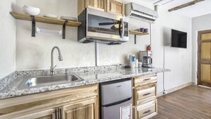 Una cucina con lavello in acciaio inossidabile, mobili in legno, forno a microonde integrato e macchina del caffè.