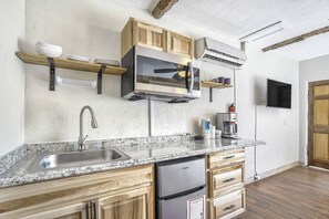 A kitchen with a stainless steel sink, wooden cabinets, a built-in microwave, and a coffee maker. - Aspen Room | Kitchenette in Manitou Springs, CO (Colorado Springs)
