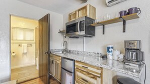 Una cucina compatta con forno a microonde integrato, macchina del caffè e frigorifero.
