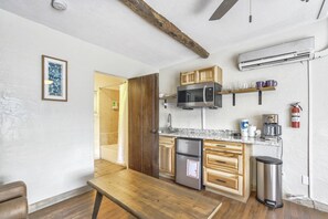 A compact kitchen with a microwave, coffee maker, and a trash bin.