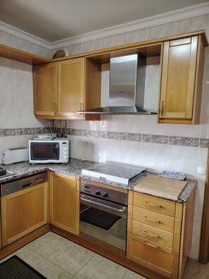 Eine Küche mit Holzausstattung, einer Mikrowelle, einem Toaster, einem Gasherd und einem Spülbecken.