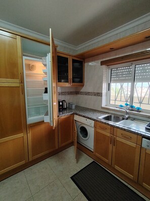 Eine Küche mit Holzausstattung, einer integrierten Waschmaschine, einem Spülbecken und einem Fenster mit Blick.