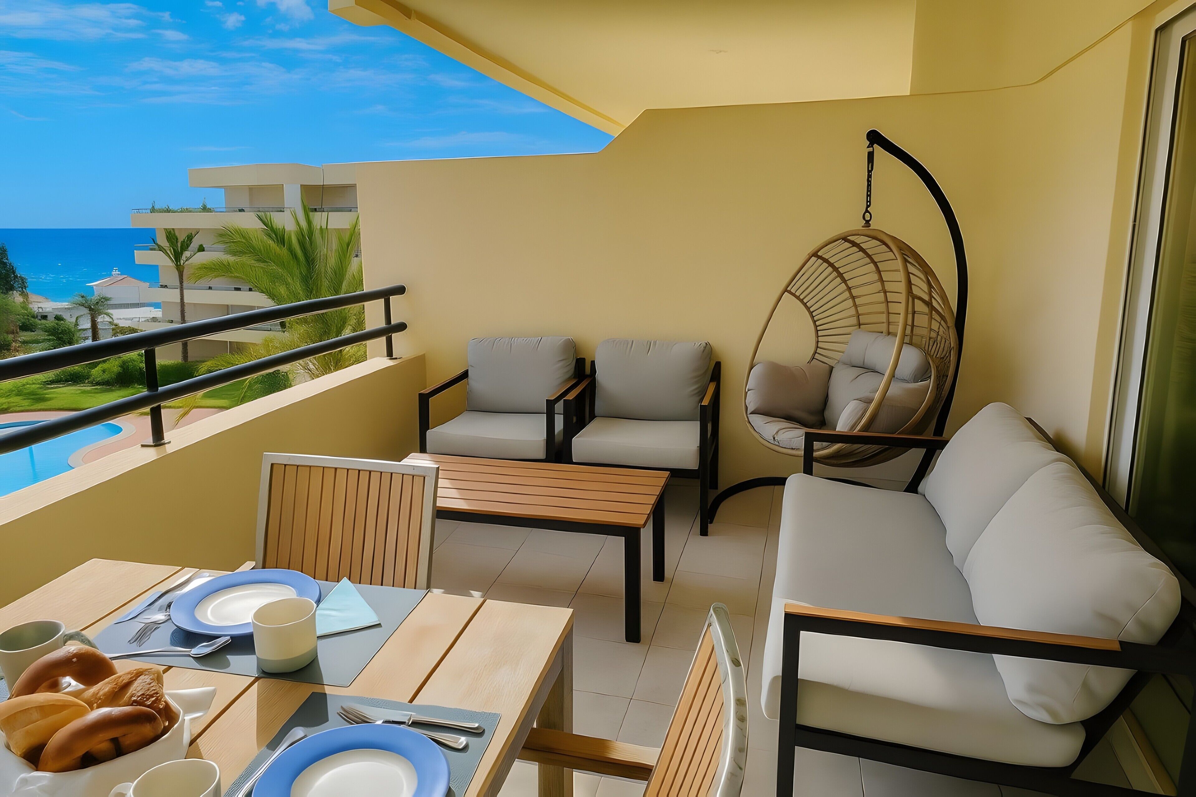 Een balkon met een eettafel voor twee personen, een hangstoel en een bank.