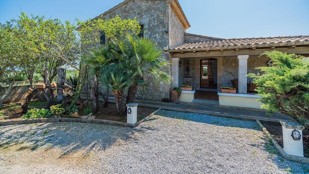 A stone building with a tiled roof, a gravel driveway, and various plants. - Peaceful Rural Haven With Pool (Pollença)
