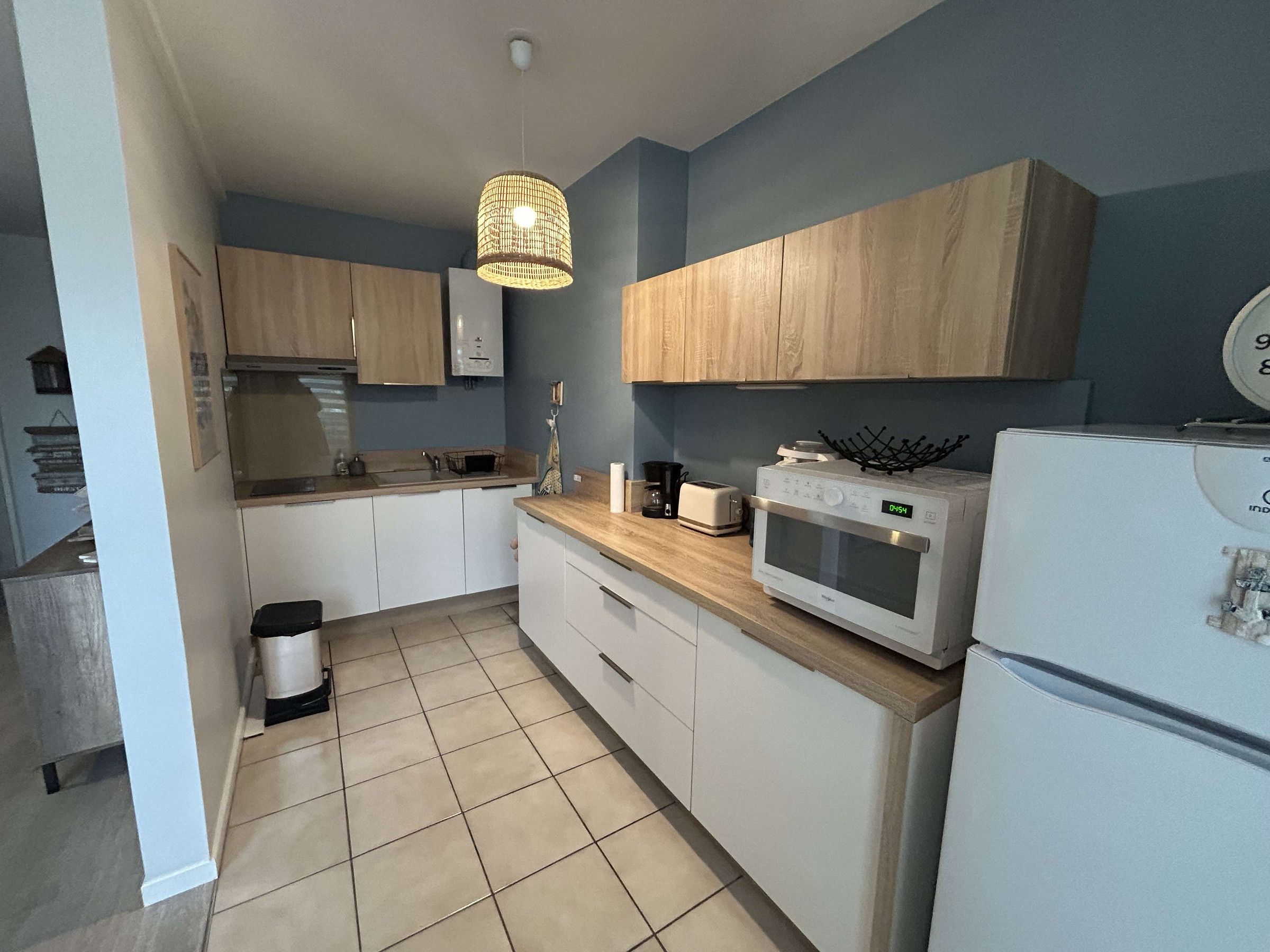 A kitchen with white cabinets, a microwave, a toaster, and a hanging light fixture.