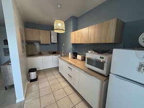 A kitchen with white cabinets, a microwave, a toaster, and a hanging light fixture. - Renovated T3 apartment with AC - Balaruc (Balaruc-les-Bains)