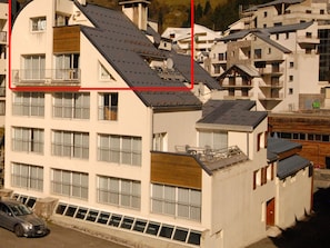 A multi-story building with balconies, a car parked in front, and a mountainous backdrop. - Spacious apartment 8-12 guests with slope view (Gourette)