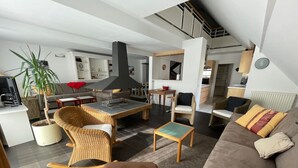 A modern living room with a sofa, chairs, a dining table, and a kitchen area in the background. - Spacious apartment 8-12 guests with slope view (Gourette)