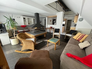 A modern living room with a sofa, chairs, a dining table, and a kitchen area in the background. - Spacious apartment 8-12 guests with slope view (Gourette)