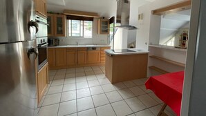 A kitchen with stainless steel appliances, wooden cabinets, a window, and a tiled floor. - Spacious apartment 8-12 guests with slope view (Gourette)