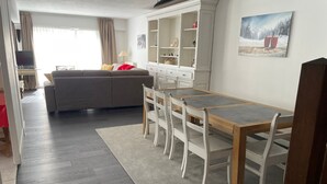 A modern living space with a dining area, sofa, and a white cabinet. - Spacious apartment 8-12 guests with slope view (Gourette)