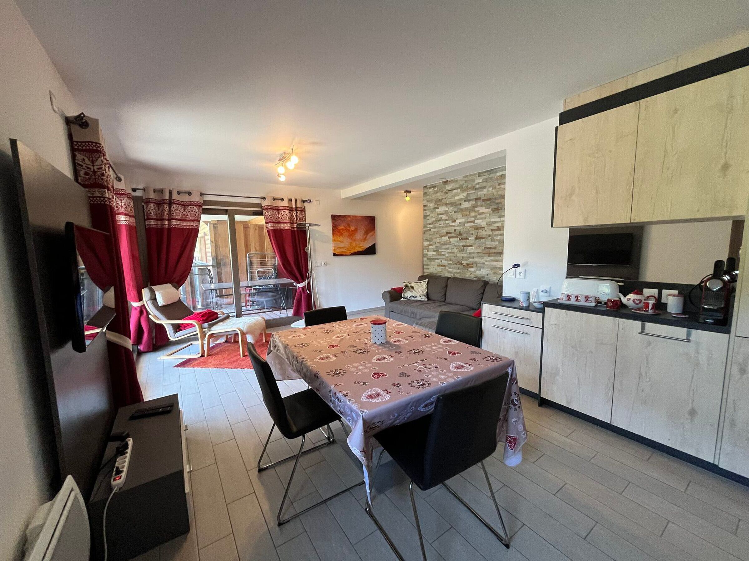 A compact living space with a dining area, kitchenette, and a sliding glass door leading to an outdoor area.