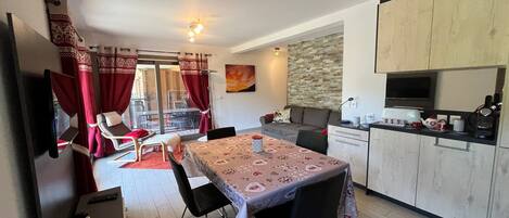 A compact living space with a dining area, kitchenette, and a sliding glass door leading to an outdoor area.