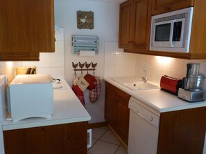 A kitchen with wooden cabinets, a microwave, a toaster, and a dishwashing machine. - Charming apartment at the foot of the slopes - 6 guests (Arêches-Beaufort)